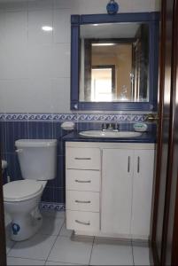 y baño con aseo, lavabo y espejo. en Habitaciones MAAZ, en Quito