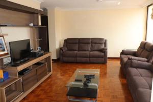 sala de estar con sofá y TV en Habitaciones MAAZ, en Quito