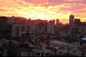 un perfil urbano con una puesta de sol en el fondo en Habitaciones MAAZ, en Quito