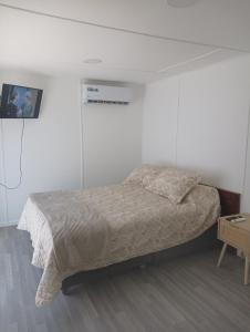a white bedroom with a bed and a table at Container home in Santa Teresa de Lo Ovalle