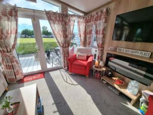 a living room with a red chair and a flat screen tv at Kimadalyn in Forfar