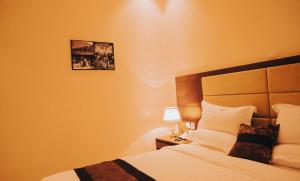 キガリにあるMadras Hotel and Apartmentsのベッドと壁に絵が飾られた寝室 +25枚の写真