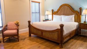 a bedroom with a large bed and a chair at La Pensione Inn - Adult Exclusive in Key West