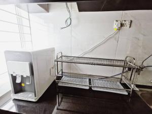 a metal shelf in a kitchen with a microwave at Bdr Seri Botani ipoh-nordic (tvbox/mahjong 19pax) in Ipoh +63 photos