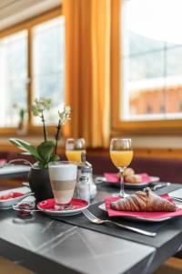 a table with plates of food and two glasses of wine at Hotel Appartement Haus Gitschberg in Vandoies