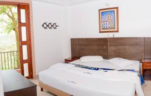 a bedroom with a large white bed and a window at Rincon Oibano in Oiba