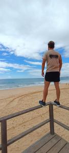 un homme debout sur une clôture à la plage dans l'établissement Villa Algarve, à Alcantarilha
