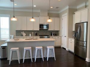 a kitchen with white cabinets and a island with bar stools at 30A Coastal Home Walk to Beach, Lake & Pool in Inlet Beach