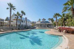 a large swimming pool with palm trees and houses at 30A Coastal Home Walk to Beach, Lake & Pool in Inlet Beach