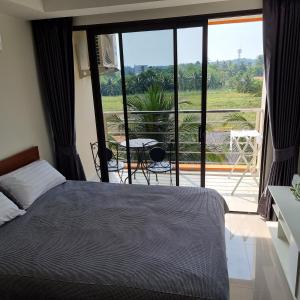 1 dormitorio con cama y vistas a un balcón en 777 Beach Condo Phuket en Mai Khao Beach
