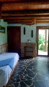 1 dormitorio con cama y ventana grande en Praia do Rosa Kaora Cabanas, en Praia do Rosa