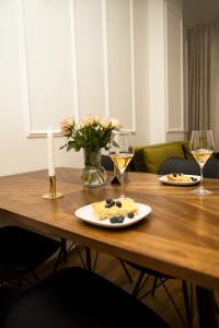 a wooden table with two plates of food and wine glasses at Room21 FREE GARAGE in Novi Sad