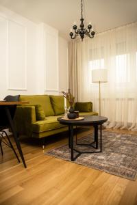 a living room with a green couch and a table at Room21 FREE GARAGE in Novi Sad