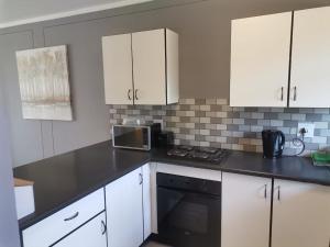 una cucina con armadi bianchi e piano di lavoro nero di Menlyn Maine Apartments, Menlyn Place a Pretoria
