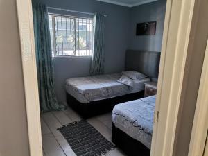 una piccola camera con due letti e una finestra di Menlyn Maine Apartments, Menlyn Place a Pretoria