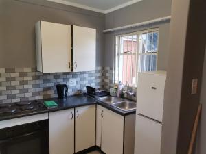 una cucina con armadi bianchi e lavandino di Menlyn Maine Apartments, Menlyn Place a Pretoria