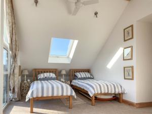two beds in a attic room with a window at The Old School House in Lonbain