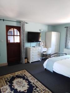 a bedroom with a bed and a desk and a television at The Catkins, Grove flock farm in Diss