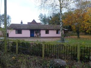 a white house with a dog sitting in the doorway at The Catkins, Grove flock farm in Diss