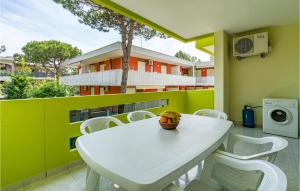 een witte tafel en stoelen op een balkon met een gebouw bij Amazing Apartment In Bibione With Outdoor Swimming Pool in Bibione