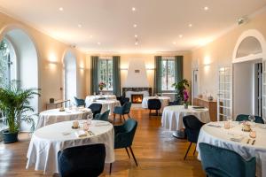 un restaurant avec des tables blanches, des chaises et des fenêtres dans l'établissement Domaine Mont-Riant à Jurançon, à Jurançon