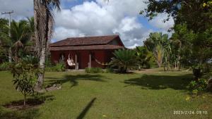 uma casa vermelha no meio de um quintal em Chale do vale em Porto Seguro