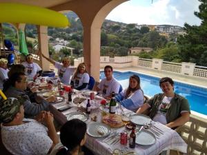 un grupo de personas sentadas alrededor de una mesa con una piscina en Villa & private swimming pool, 20 min from beach, en Maçanet de la Selva