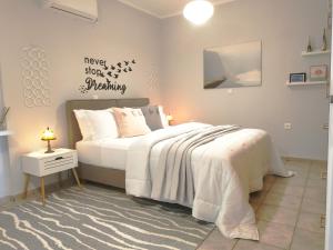 a bedroom with a white bed with akeep slowapping sign on the wall at Harris elegant house superb view near airport in Artemida