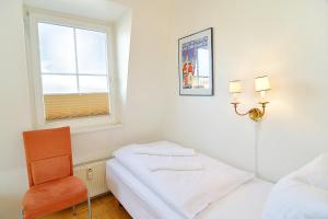 a small white room with a bed and a chair at Hamburg-App-08 in Ahlbeck