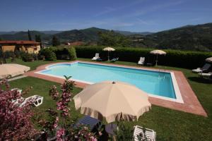 a swimming pool with an umbrella and some chairs at Trebbiolo in Dicomano