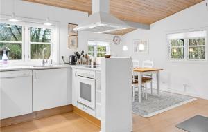 a kitchen with white cabinets and a table in it at 3 Bedroom Nice Home In Aakirkeby in Vester Sømarken