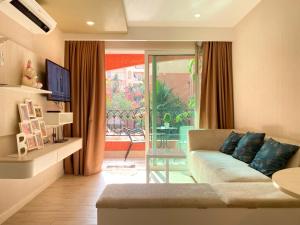 ein Wohnzimmer mit einem Sofa und einer Glasschiebetür in der Unterkunft Seven Seas Condo Resort Jomtien Pattaya #Pool View #Near Beach in Jomtien Beach