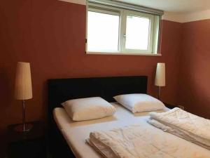 een slaapkamer met een bed met 2 kussens en een raam bij Sfeervol vakantiehuis op de Veluwe 2-6 personen in Putten