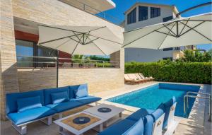 a swimming pool with blue furniture and an umbrella at Amazing Home In Zaton With Heated Swimming Pool in Zaton