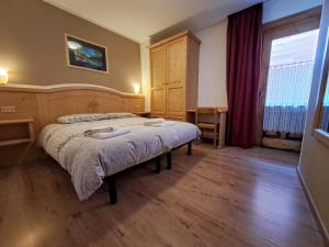 Un dormitorio con una cama y una ventana grande. en Casa Anita, en Livigno