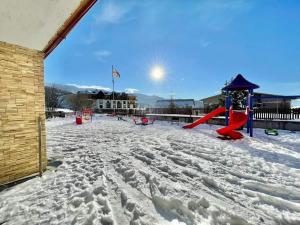 un parco giochi coperto di neve accanto a un edificio di HORIZONT a Bakuriani