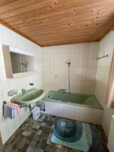 ein Badezimmer mit einer grünen Badewanne und einem Waschbecken in der Unterkunft Ferienhaus Reinhard Steiner in Hinterbichl
