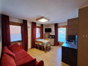 Una sala de estar con un sofá rojo y una mesa. en Casa Anita, en Livigno