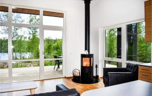 uma sala de estar com um fogão a lenha em frente às janelas em Beautiful Home In Holmsj With Sauna em Holmsjö