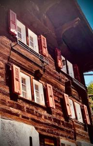 - un bâtiment en briques avec des fenêtres et des volets dans l'établissement Luxury & Cosy 3.5 rooms apartment in almost 300 years old Chalet, à Loèche-les-Bains