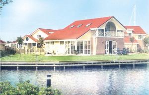uma casa com um telhado vermelho ao lado de um corpo de água em It Soal Waterpark-waterlelie em Workum