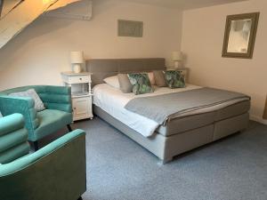 - une chambre avec un grand lit et une chaise dans l'établissement Hotel SPA Restaurant Au Cheval Blanc, à Ribeauvillé