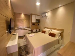 a small bedroom with a bed and a kitchen at Suíte ACONCHEGO no Villa do porto a 300m do Beach Park e a 5 minutos a pé da praia in Aquiraz