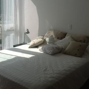 1 cama blanca con almohadas en el dormitorio en areia beach paradaise, en Santa Marta