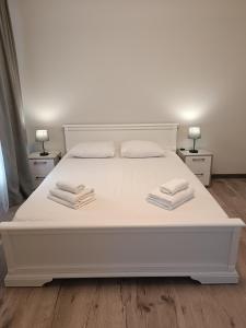 - une chambre avec un lit blanc et des serviettes dans l'établissement Apartments Domovik Трьохкімнатна квартира , європейського стилю, à Moukatcheve
