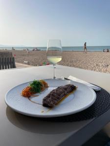 a plate of food and a glass of wine on the beach at Oliva Seaside Apartments in Oliva