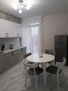 - une cuisine avec une table et des chaises blanches dans la chambre dans l'établissement Apartments Domovik Трьохкімнатна квартира , європейського стилю, à Moukatcheve