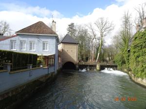 een rivier met een gebouw naast een brug bij Une nuit près de l eau in Hallines