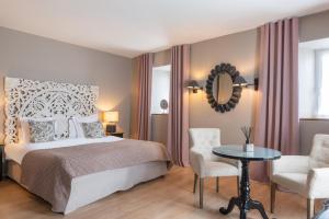 a bedroom with a bed and a table and chairs at Hôtel Traiteur Les Ormes, The Originals Relais in Barneville-Carteret