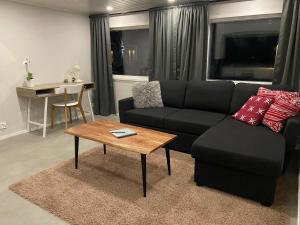 a living room with a black couch and a table at StrandRo - mökki järven rannalla in Luoto